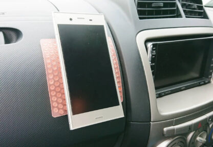 車のダッシュボードに貼られたビタシートにスマートフォンが貼り付いている様子。